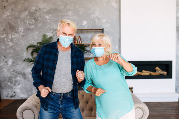 Старшая пара в масках для лица танцует в помещении