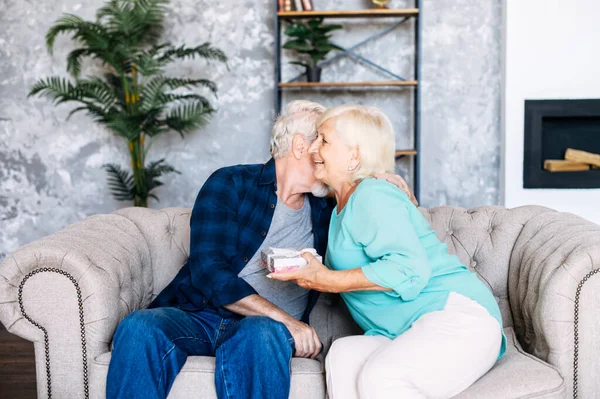 Idősebb férfi ajándékot ad egy idős nőnek otthon. — Stock Fotó