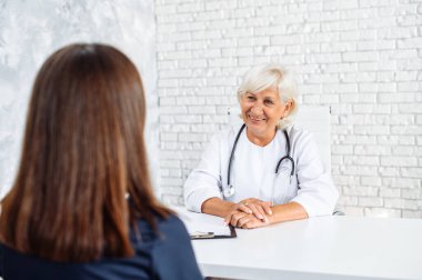 Kıdemli bayan doktor hastaya danışmanlık yapıyor.