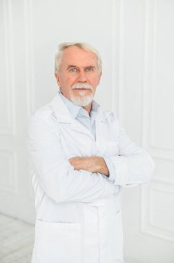 Beyazın üstündeki yaşlı gri saçlı erkek doktor.