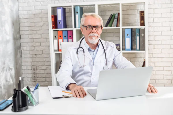 Senior medico maschio con una stethoscpe utilizzando il computer portatile — Foto Stock