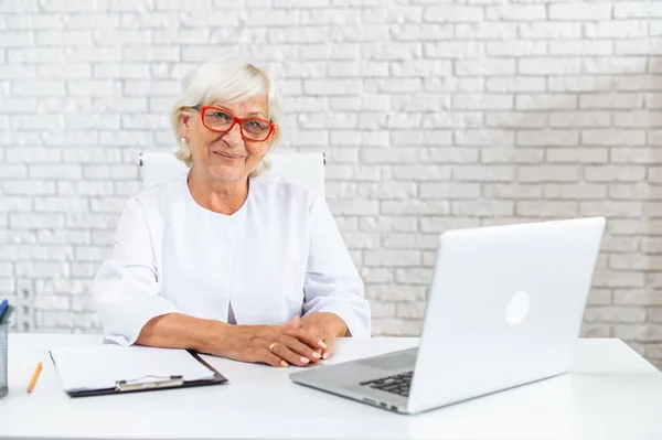 Старшая женщина-врач консультирует пациента онлайн — стоковое фото