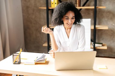 Genç bir kadın ofiste dizüstü bilgisayar kullanıyor.