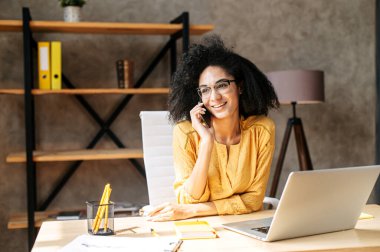 Genç bir kadın ofiste dizüstü bilgisayar kullanıyor.