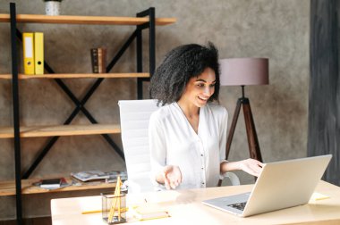 Genç bir kadın ofiste dizüstü bilgisayar kullanıyor.