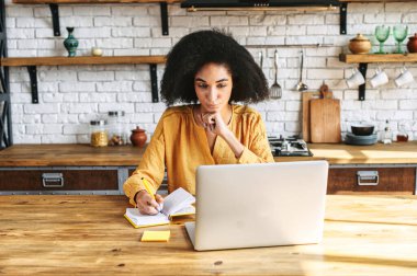 Afro-Amerikalı genç bir kadın dizüstü bilgisayar kullanıyor.