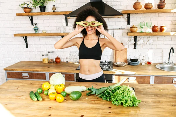 A healthy woman with an avocado at kitchen