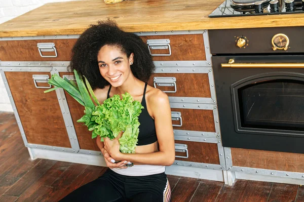 En frisk kvinna med grönsaker i köket — Stockfoto