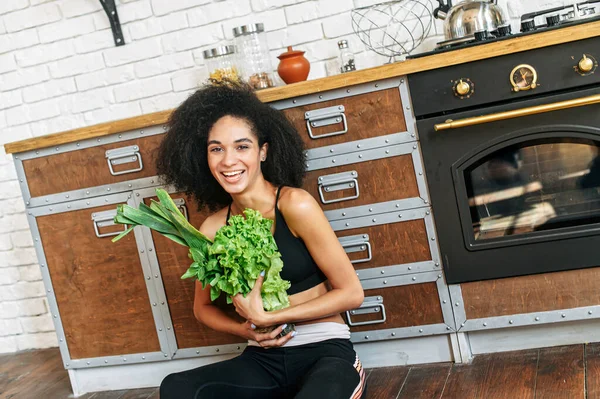 En frisk kvinna med grönsaker i köket — Stockfoto
