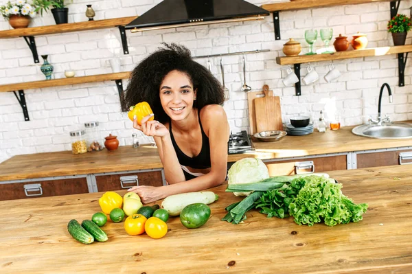 Een gezonde vrouw met een groente in de keuken — Stockfoto