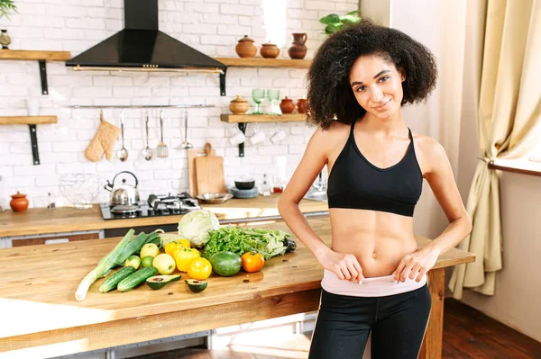 Een gezonde vrouw met een groente in de keuken — Stockfoto
