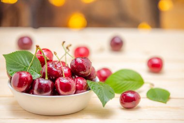 Ahşap masada beyaz kase taze kiraz