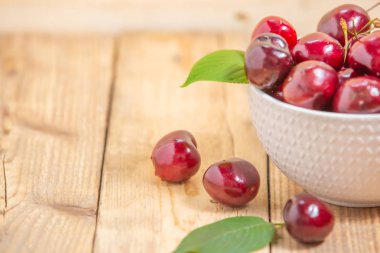 Ahşap masada beyaz kase taze kiraz