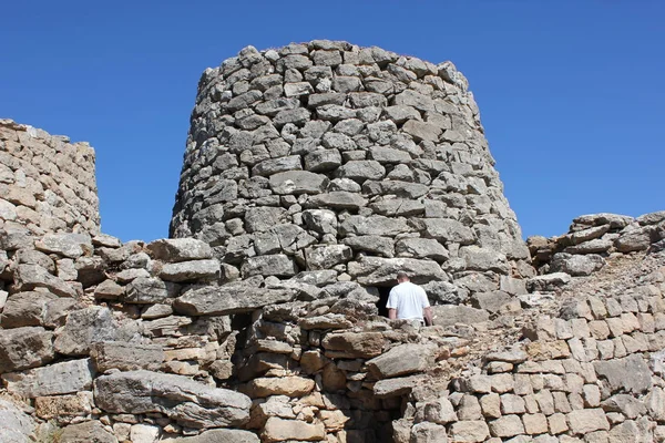 A man entering into a Nuraghe, a typical ancient rock building of the Sardinia island.