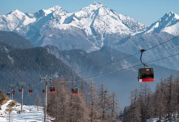 Rad av linbanor mot snöiga italienska bergen. — Stockfoto