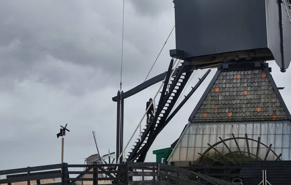 Homme traversant l'escalier sur les moulins à vent par une journée nuageuse et venteuse - South holland - Groupe de 19 moulins monumentaux - Molens de Kinderdijk . — Photo