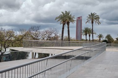Bulutlu bir günde arka planda modern Kule ve avuç içi ile Sevilla nehir boyunca görünümü.