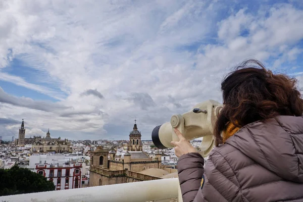 Kvinna tittar med teleskop på observationsdäcket med utsikt över Sevilla i en molnig dag - Spanien huvudstad i Andalusien. — Stockfoto