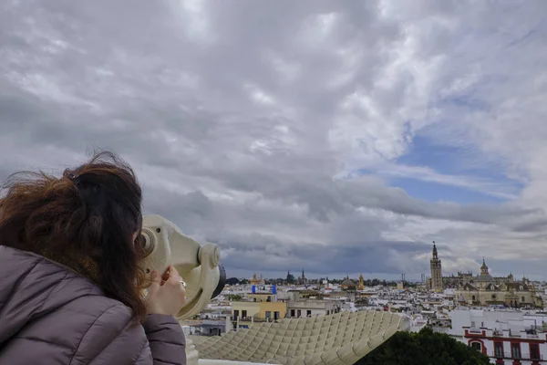 Kvinna tittar med teleskop på observationsdäcket med utsikt över Sevilla i en molnig dag - Spanien huvudstad i Andalusien. — Stockfoto