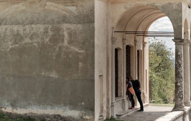 Kutsal Dağı veya Varese Sacro Monte tarihi hac güzergahı yolu boyunca şapel içinde bakan erkek ve kadın, İtalya