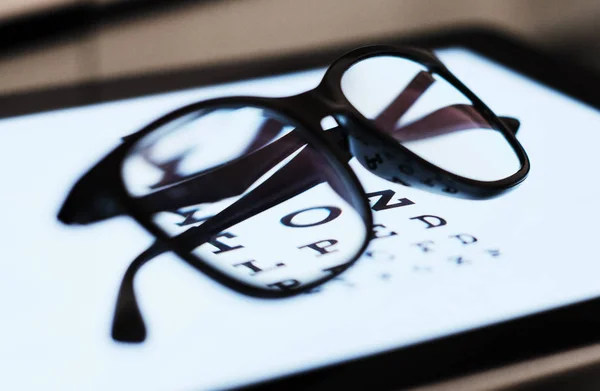 Gráfico ocular no comprimido e no vidro com E Standard Logarithm Eyesight Tablet na parte superior da tela de luz — Fotografia de Stock