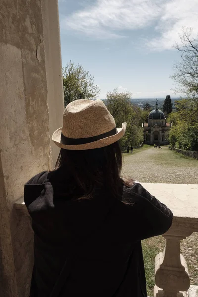 Traveler flicka med Vintage halm hatt ser monumets och en av Xivchapel längs vägen för den historiska pilgrimsfärdsleden från Sacred Mount eller Sacro Monte i Varese, Italien — Stockfoto
