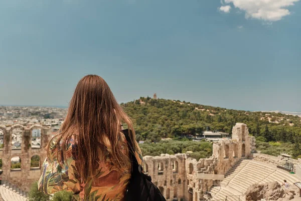 Flicka med röda hårstrån och färgglada klänning ta foto med sin smarta telefon till Aten Grekland, teater under Akropolis-Odeon av Herodes Atticus . — Stockfoto