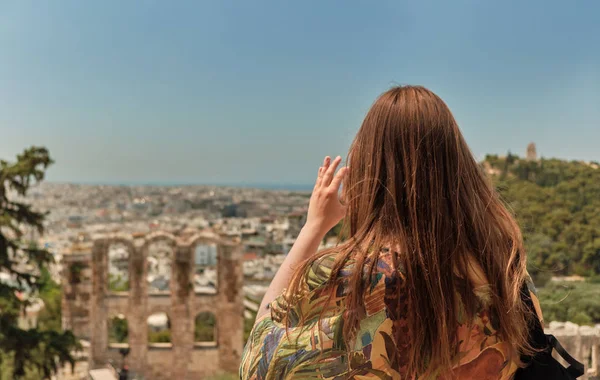 Flicka med röda hårstrån och färgglada klänning ta foto med sin smarta telefon till Aten Grekland, teater under Akropolis-Odeon av Herodes Atticus. — Stockfoto