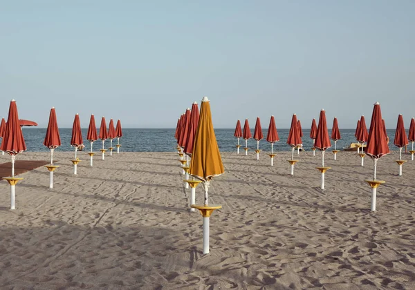 Muster oder Gruppe roter Sonnenschirme Meer am Strand bei Sonnenuntergang - Regelbruch. — Stockfoto