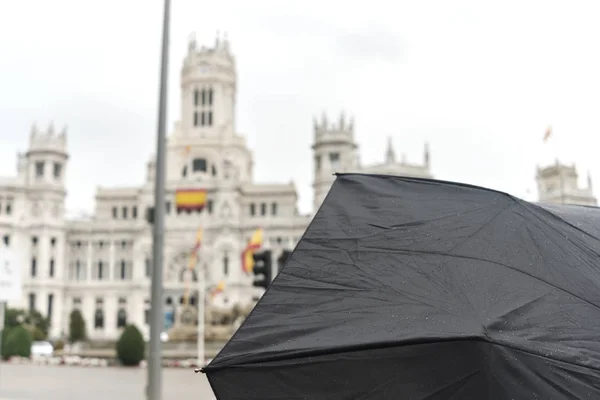 Paraguas con famoso edificio visitando madrid en un día lluvioso . — Foto de Stock
