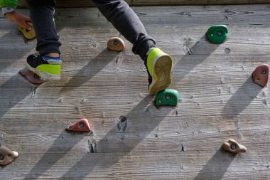 Güneşli bir günde çocukların oyun parkında tırmanma duvarında oynayan bir çocuk.
