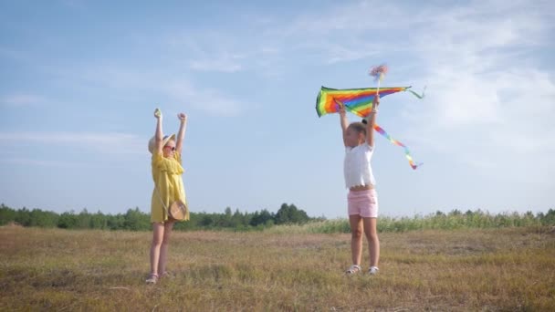 Граючи з повітряним змієм, милі подруги дівчат насолоджуються відпочинком на відкритому повітрі, запускаючи повітряну іграшку під час вихідних у лісі в сонячний день проти блакитного неба — стокове відео