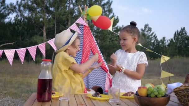 Juegos para niños, divertidas novias juegan piedra tijera de papel durante el almuerzo en el picnic en el bosque en el fondo de wigwam — Vídeos de Stock