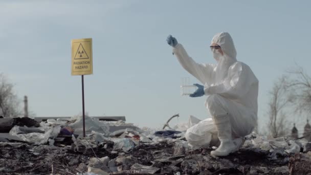 Biologische Gefahr, Wissenschaftlerin Ökologin in Uniform und Schutzhandschuhen entnimmt Probe des Mülls von der großen schmutzigen Deponie — Stockvideo