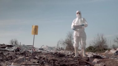 koruyucu takım elbise li kadın ve maske tutan poster ile çöplükte biyolojik tehlike yakınında dur kirliliği sloganı
