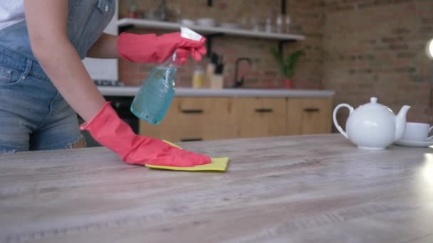 Manos femeninas en guantes con trapo limpiando fácilmente la mesa del polvo y manchas con detergente en la cocina — Vídeo de stock