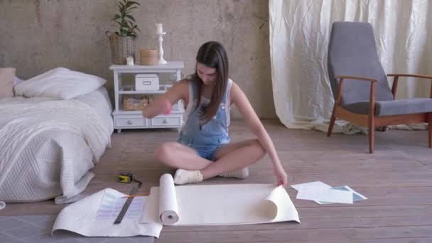 Amélioration de la maison, les mesures de la jeune femme et des coupes papier peint pour réparer la pièce sur le sol dans un nouvel appartement — Video