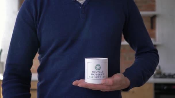 Kullanılan pilleri toplama, adam uluslararası geri dönüşüm logosu üç kovalayan oklar ile konteyner içine eski piller koyar sonra başparmak kadar jest göstermek — Stok video