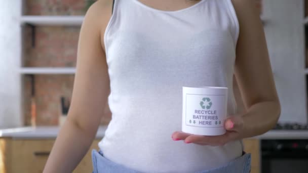 Concept écologique, jeune femme place les piles usagées dans une boîte avec phrase recycler les piles ici et les flèches vertes puis montrer pouce vers le haut geste — Video