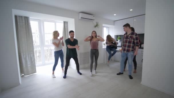 Festa em casa, amigos multinacionais tendo corridas de piggyback uns contra os outros no apartamento em câmera lenta — Vídeo de Stock