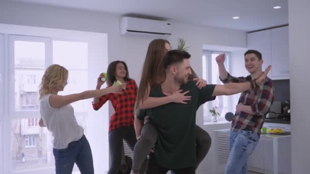 Alegres jóvenes amigos multinacionales en apartamento compartido divirtiéndose y bailando disfrutando de las vacaciones en casa fiesta — Vídeo de stock