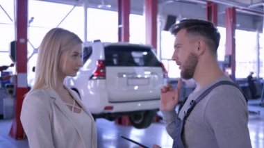 araba servisi, elinde tablet bilgisayar ile işçi hidrolik asansör aracın arka plan üzerinde bir kadın müşteri ile konuşurken