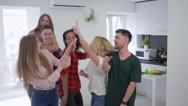 Multirasistiska vänner dansar och ha kul i köket, pojkar och flickor lurar runt på en hemmafest i slow motion — Stockvideo