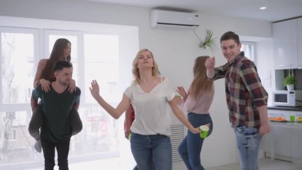 Multiraciale groep van vrienden leuk dansen met plastic bekers in hun handen in grote moderne appartement op een Home Party — Stockvideo