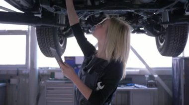 kadın araba tamircibacklight tablet ile tamir servis istasyonunda kaldırdı otomobil inceleyerek