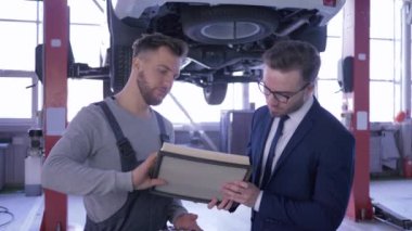 mekanik görüşmeler ve servis istasyonunda bir asansör üzerinde otomobilin arka planda müşteriye motor hava filtresi göstermek