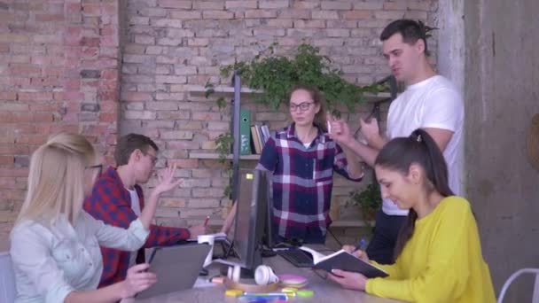 Šťastní pracovníci v kanceláři diskutují obchodní myšlenku v tabulce a dělají poznámky v poznámkovém bloku a tabletovém počítači — Stock video