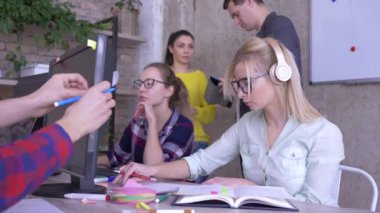 iş yerinde insanlar, genç ekip modern ofiste bir iş planı üzerinde çalışıyor sonra kız kameraya bakar ve gülümsüyor