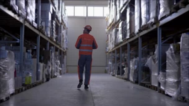 Trabalhador de armazém com copos em capacete duro e uniforme faz notas no tablet durante realiza uma auditoria — Vídeo de Stock