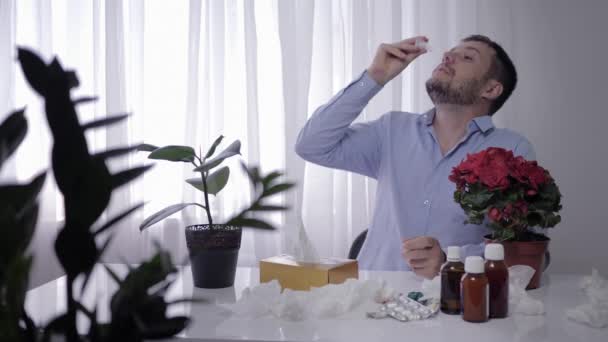 Domestic allergies, sick man suffers from seasonal infection and takes medical drops and wiped in a handkerchief at sitting a table in room — Stock Video